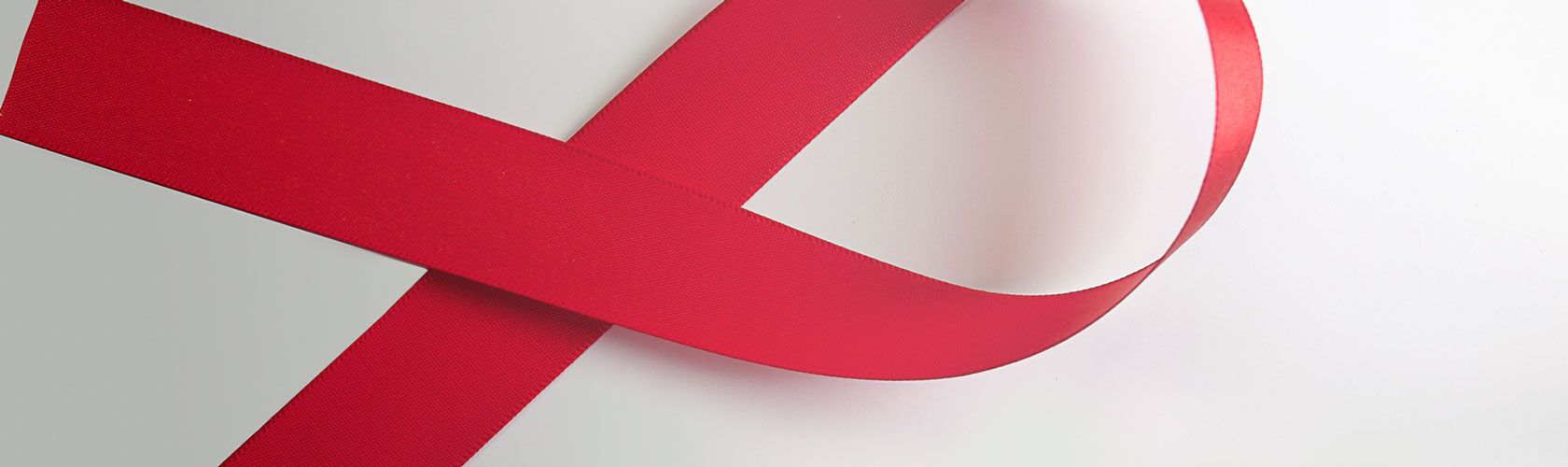 Ein rotes Band in Schleifenform symbolisiert das Bewusstsein für HIV/AIDS auf einem hellen Hintergrund.