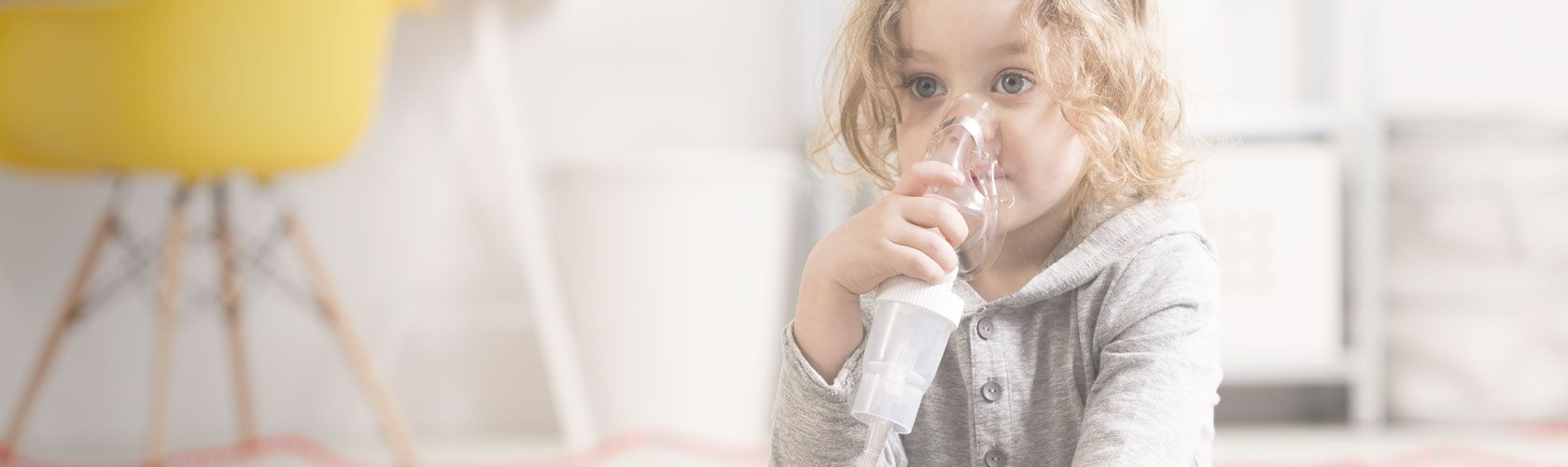 Ein kleines Kind nutzt ein Inhalationsgerät zur Atemunterstützung in einem hellen Raum.